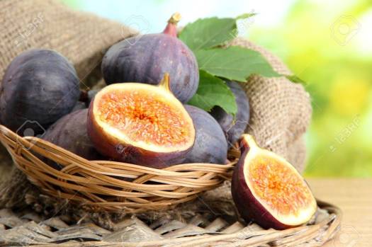 15994791-ripe-sweet-figs-with-leaves-in-basket-on-wooden-table-on-green-background